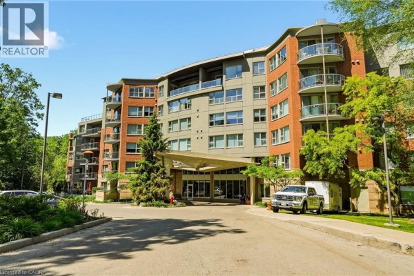 Modern apartment building exterior with brick and grey facade, balconies, and entrance canopy. - 77 Governor's Road Unit# 404, Dundas