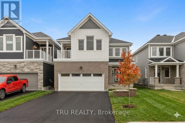 Front view of a newly built detached house with a red truck parked in the driveway and autumn foliage. - 77 Hackamore Crescent, Ottawa