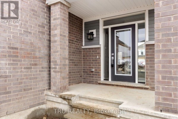 Covered front porch with gray brick pillars, a glass front door, and a light fixture. - 77 Hackamore Crescent, Ottawa