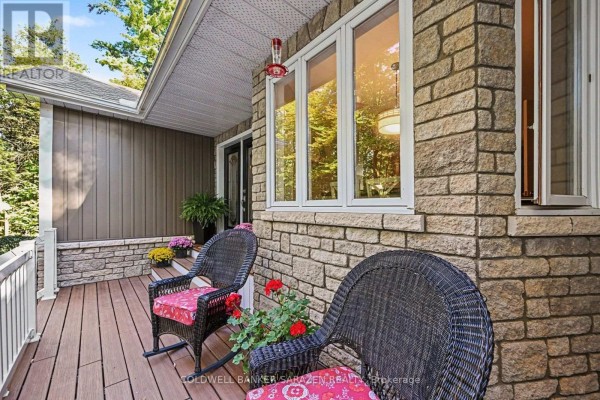 Front porch with wicker chairs and a view through the stone-accented windows. - 77 Lorlei Drive, Mcnab/braeside