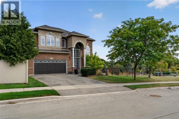 Front view of a brick two-story house with a double garage and green lawn. - 77 Newcombe Road, Dundas