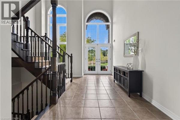 Foyer with tiled floor, dark wood staircase, and double front doors with large arched windows. - 77 Newcombe Road, Dundas