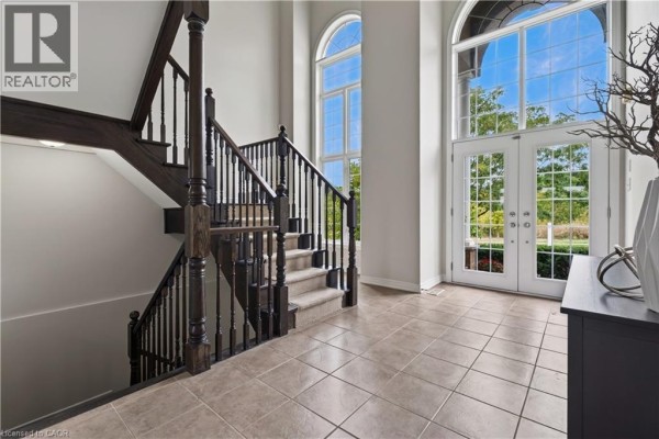 Interior foyer with tiled floor, view of the dark wood staircase, and double front doors. - 77 Newcombe Road, Dundas