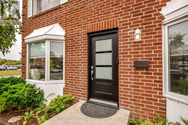 Close-up of the red brick exterior showing a black front door with glass panes and a mailbox. - 77 Pepler Place, Barrie