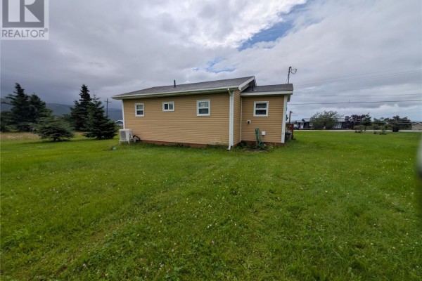 Rear exterior of the beige house with two windows and an air conditioning unit visible. - 77 Point Au Mal Road, Point Au Mal