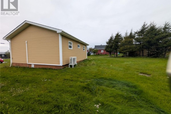Side view of the beige house showing the yard and neighboring properties in the background. - 77 Point Au Mal Road, Point Au Mal