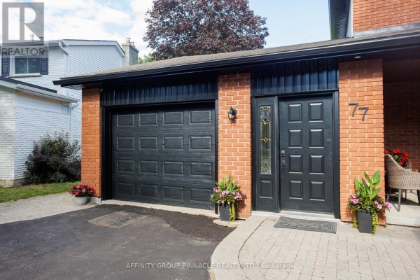 Close-up of the black garage door, black front door with glass panels, and brick exterior. - 77 Sanderling Crescent, Kawartha Lakes