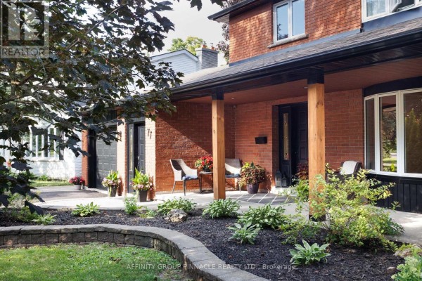 View of the covered front porch with seating, brick exterior, and mature landscaping. - 77 Sanderling Crescent, Kawartha Lakes
