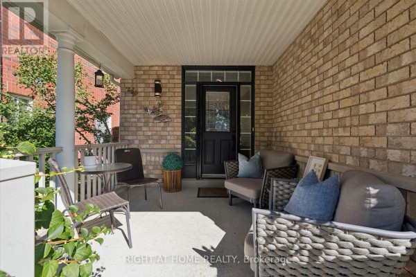 Covered front porch with brick walls, wicker chairs, and a glass-paneled front door. - 77 Shoniker Drive, Newmarket