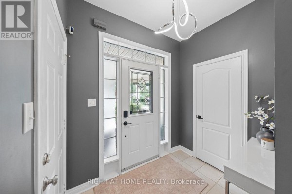 Interior entryway with dark gray walls, tiled floor, and a white front door with glass sidelights. - 77 Shoniker Drive, Newmarket