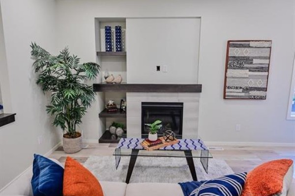 Living room features a gas fireplace with tiled surround, dark wood mantle, and two built-in shelves. - 77 Spruce Cove, West St Paul