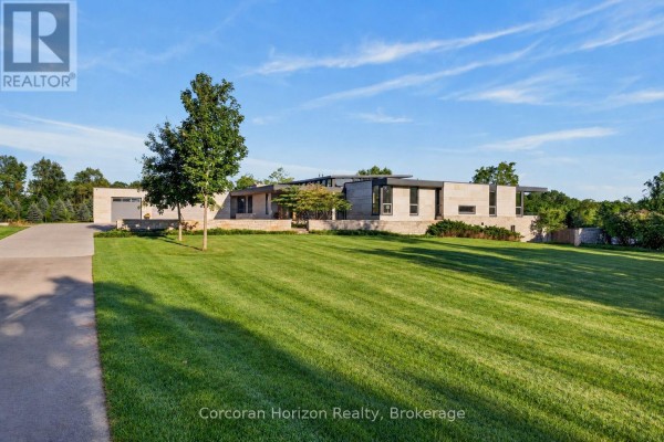 Front exterior of a long, low-profile modern home with stone facade and manicured lawn. - 770 Millgrove Side Road, Hamilton
