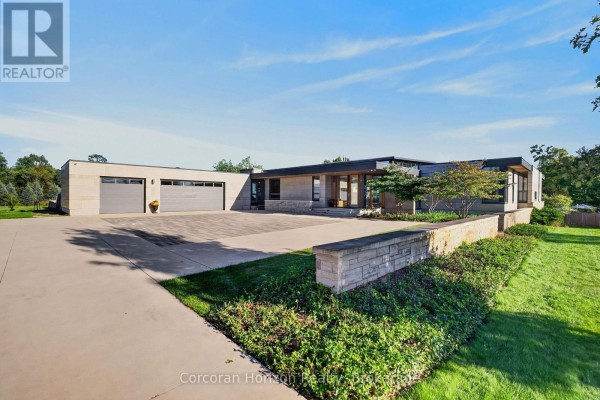 View of the modern home's stone facade, attached garage, and paved driveway. - 770 Millgrove Side Road, Hamilton