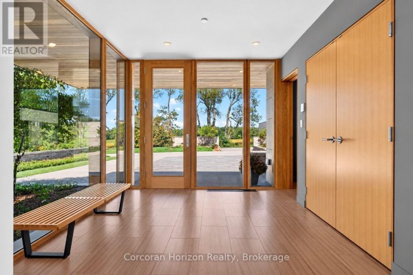 Entryway with wood-paneled walls, bamboo bench, tile flooring, and glass doors. - 770 Millgrove Side Road, Hamilton