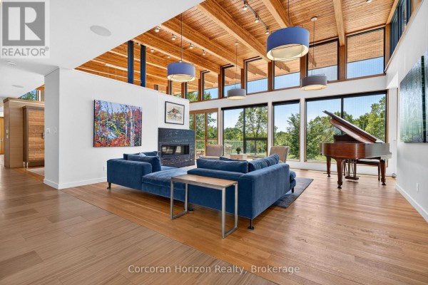 Living room with blue sectional sofa, fireplace, grand piano, wood-beamed ceiling, and large windows. - 770 Millgrove Side Road, Hamilton