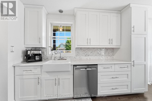 Kitchen sink area with white cabinets, granite countertops, a farmhouse sink, and a window. - 770 Scott Street W, North Perth
