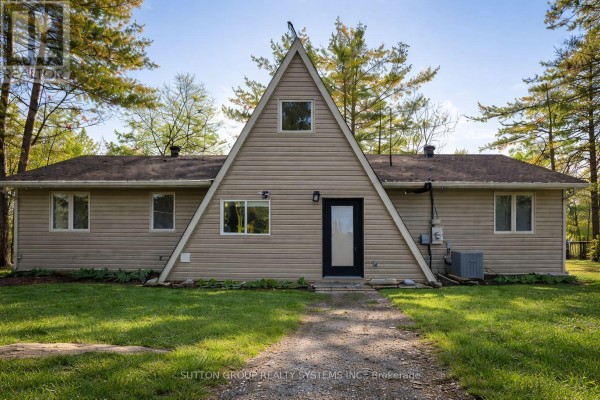 A-frame style house with beige siding and large front windows - 7701 Doner Drive, Severn