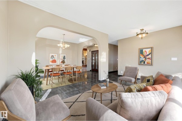 Open-concept living and dining area with arched doorways, beige sofas, armchairs, and a wooden dining table set for six. - 7708 158 Av Nw, Edmonton