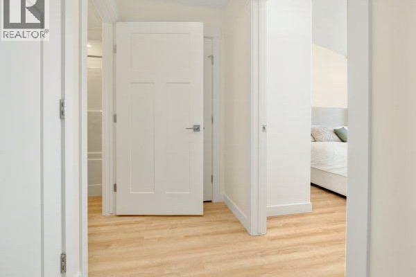 Interior hallway with light wood floors and several closed white doors leading to different rooms. - 771 7 Avenue W, Cardston