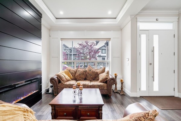 Living room fireplace with patterned sofa and a view of the street through the front window. - 7719 155 Street, Surrey