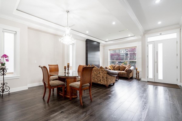 Open concept living and dining area with a round dining table, chandelier, and fireplace. - 7719 155 Street, Surrey