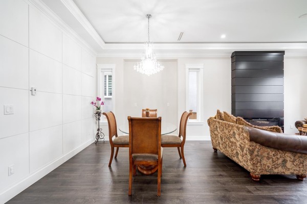 Dining area with a glass-top table, wooden chairs, and a crystal chandelier above. - 7719 155 Street, Surrey