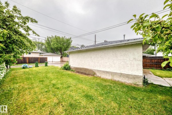 Backyard with green grass, fence, trees, and a garage. - 7723 81 Av Nw, Edmonton