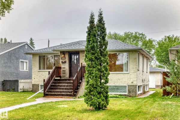Front exterior of a beige stucco house with a wooden staircase. - 7723 81 Av Nw, Edmonton