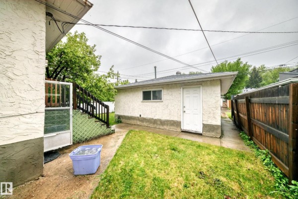 Backyard showing a side door, stairs, grass, and a fence. - 7723 81 Av Nw, Edmonton