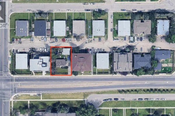 Aerial view of a residential property at 7728 Bowness Road Nw, Calgary, highlighted in red, situated between apartment buildings and across from a main road. - 7728 Bowness Road Nw, Calgary