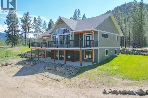 Side view of the green house with a lower level walkout and a large deck on the main floor. - 7735 Gn Road, Grand Forks