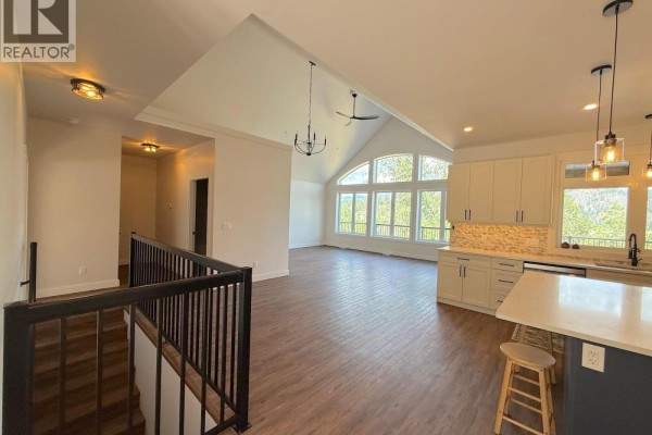 Open concept living area with vaulted ceilings, large arched windows, and a view of the kitchen island. - 7735 Gn Road, Grand Forks