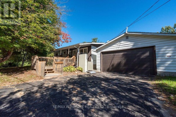 Exterior view of a house with a large garage door and a wooden deck. - 774 Pinegrove Crescent, Petawawa