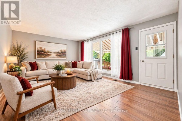 Living room with a sectional sofa, armchair, wooden coffee table, and hardwood floors. - 774 Pinegrove Crescent, Petawawa