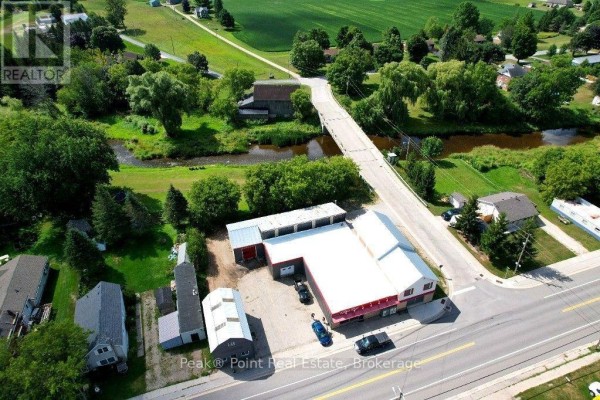 Two-story building with stone lower level and upper level, side entrance, and 'For Sale' sign. - 7740 21 Highway, South Bruce Peninsula