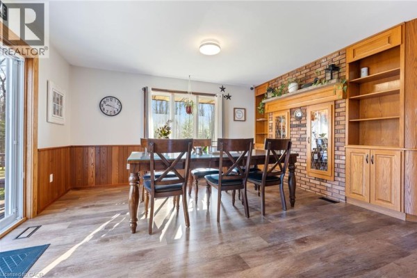 Cozy room with wood-paneled walls, sofa, small dining table, and a window overlooking fields. - 775 4th Concession Road Enr, Fairground