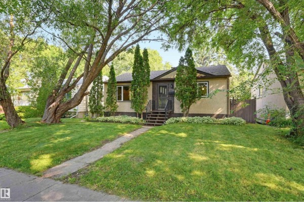 Front exterior view of a single-story house with a tan stucco exterior and manicured lawn. - 7754 80 Av Nw Nw, Edmonton