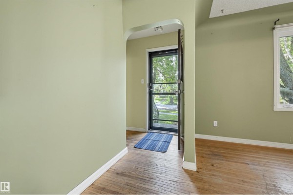 Interior view of an entryway with light green walls, a blue and white striped rug, and a screen door. - 7754 80 Av Nw Nw, Edmonton