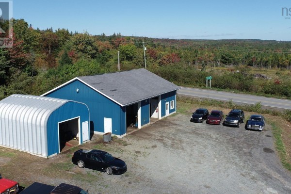 Side aerial view of the blue commercial building with arched storage and several parked vehicles. - 7756 Highway 276, Lot 1, Roachvale
