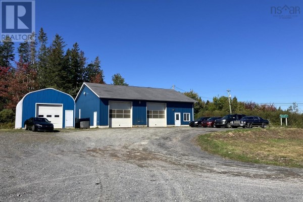 Front view of the blue commercial building with garage doors and surrounding gravel lot. - 7756 Highway 276, Lot 1, Roachvale