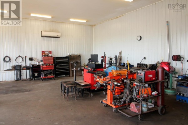 Inside workshop with metal walls, floor, welding equipment, tool chests, and air conditioner. - 7756 Highway 276, Lot 1, Roachvale