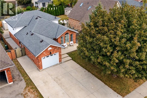 Aerial view of brick house with attached garage and large tree. - 776 Acadia Drive, Hamilton