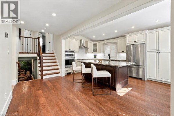 Open concept kitchen with island, white cabinets, and wood floors. - 776 Acadia Drive, Hamilton