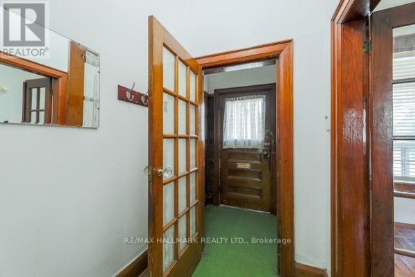 Interior hallway with hardwood trim, a glass-paneled door, and a mirror on the wall. - 776 Gerrard Street E, Toronto