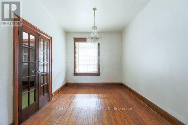 Empty dining room with hardwood floors, white walls, a window, and a chandelier. - 776 Gerrard Street E, Toronto