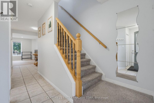 Hallway with beige tile flooring, carpeted stairs, and a full-length wavy mirror. - 776 Silversmith Street, London North