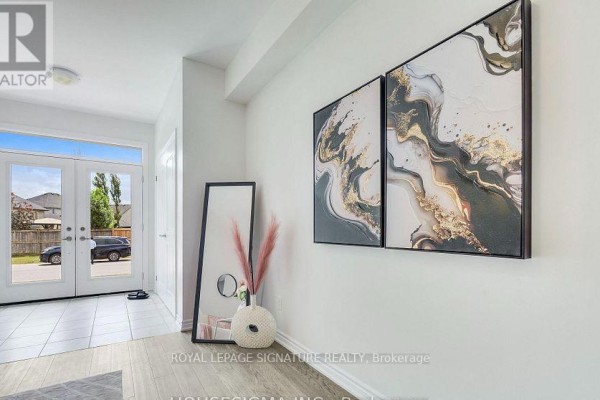 Entryway with double doors, pale grey laminate flooring, and abstract wall art. - 7763 Secretariat Court, Niagara Falls
