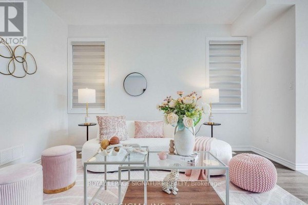 Living room with a white sofa, pink ottomans, glass coffee table, and windows with blinds. - 7763 Secretariat Court, Niagara Falls