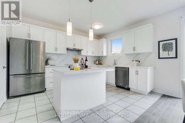 White kitchen with stainless steel appliances, a central island, and white tiled flooring. - 7763 Secretariat Court, Niagara Falls