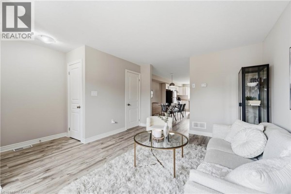 Living room with sofa, chairs, coffee table, and view of dining area and kitchen. - 7768 Ascot Circle Unit# 5, Niagara Falls